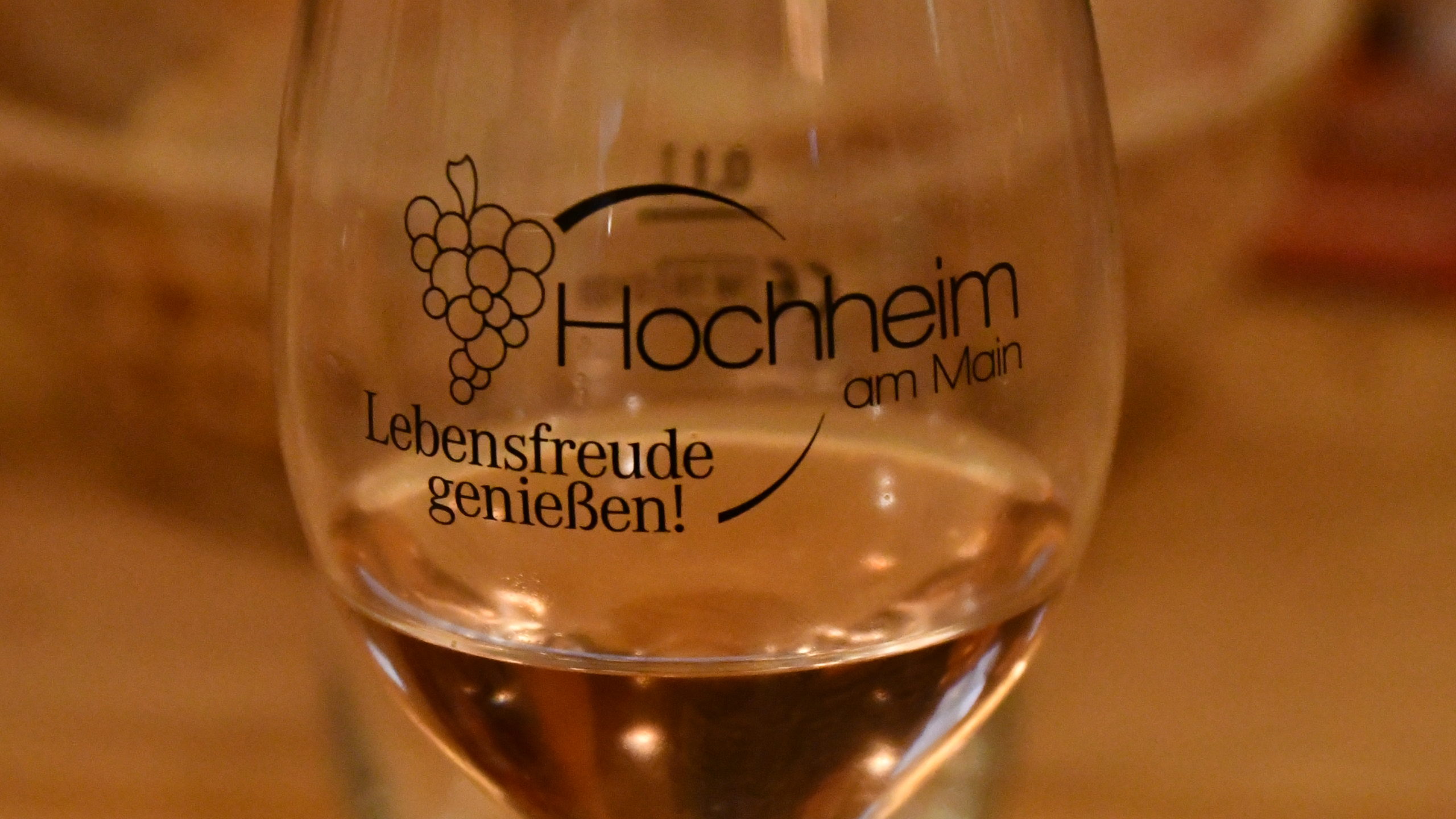 Ein mit Wein gefülltes Weinglas mit der Aufschrift Hochheim am Main und Weinreben