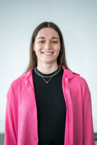 eine junge Frau mit langen dunklen Haaren in einem pinken Blazer