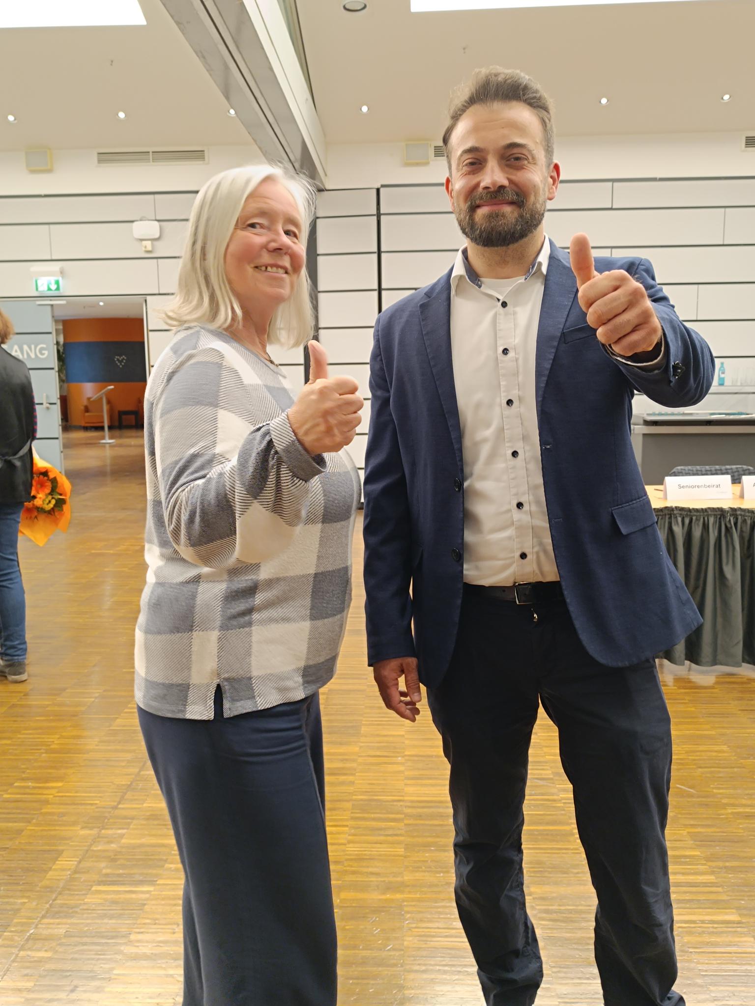 Eine Frau und ein Mann stehen gut gelaunt mit Daumen hoch im Sitzungssaal der Hofheimer Stadtverordnetenversammlung