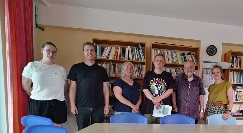 In den Geschäftsräumen von JJ stehen drei Frauen und drei Männer für ein Gruppenbild vor einem großen Bücherschrank.